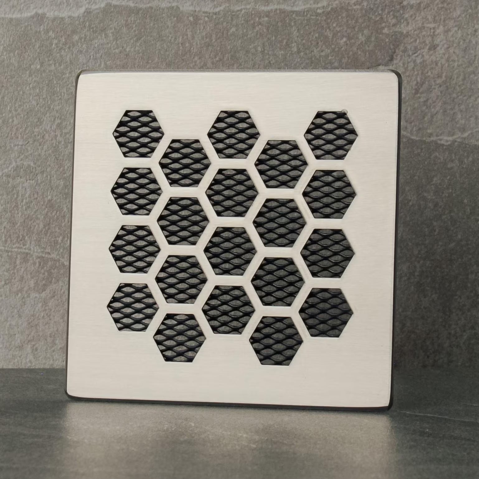 Decorative metal grille with honeycomb pattern on a gray background