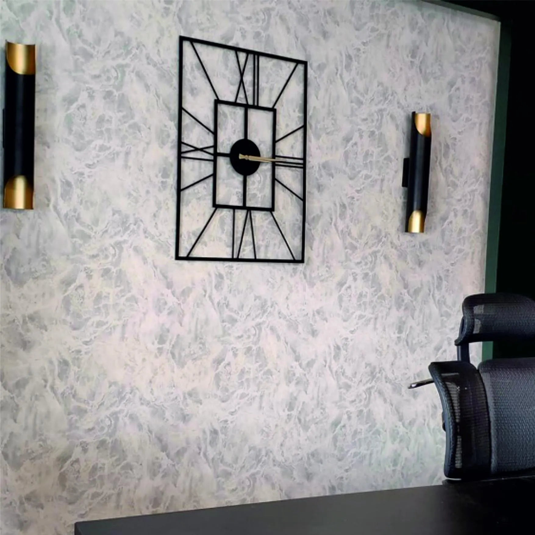 Decorative wall clock with geometric design on a textured wall with wall sconces.