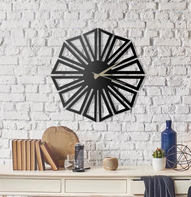 Black geometric wall clock on a white brick wall with decorative items below.