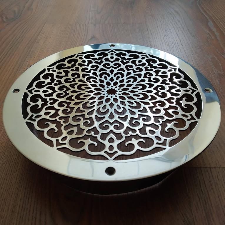Decorative metal grille with intricate patterns on a wooden surface
