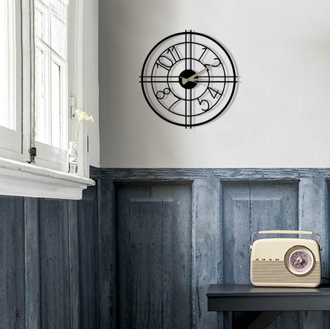 Decorative wall clock on a gray wall with a vintage radio on a table below.