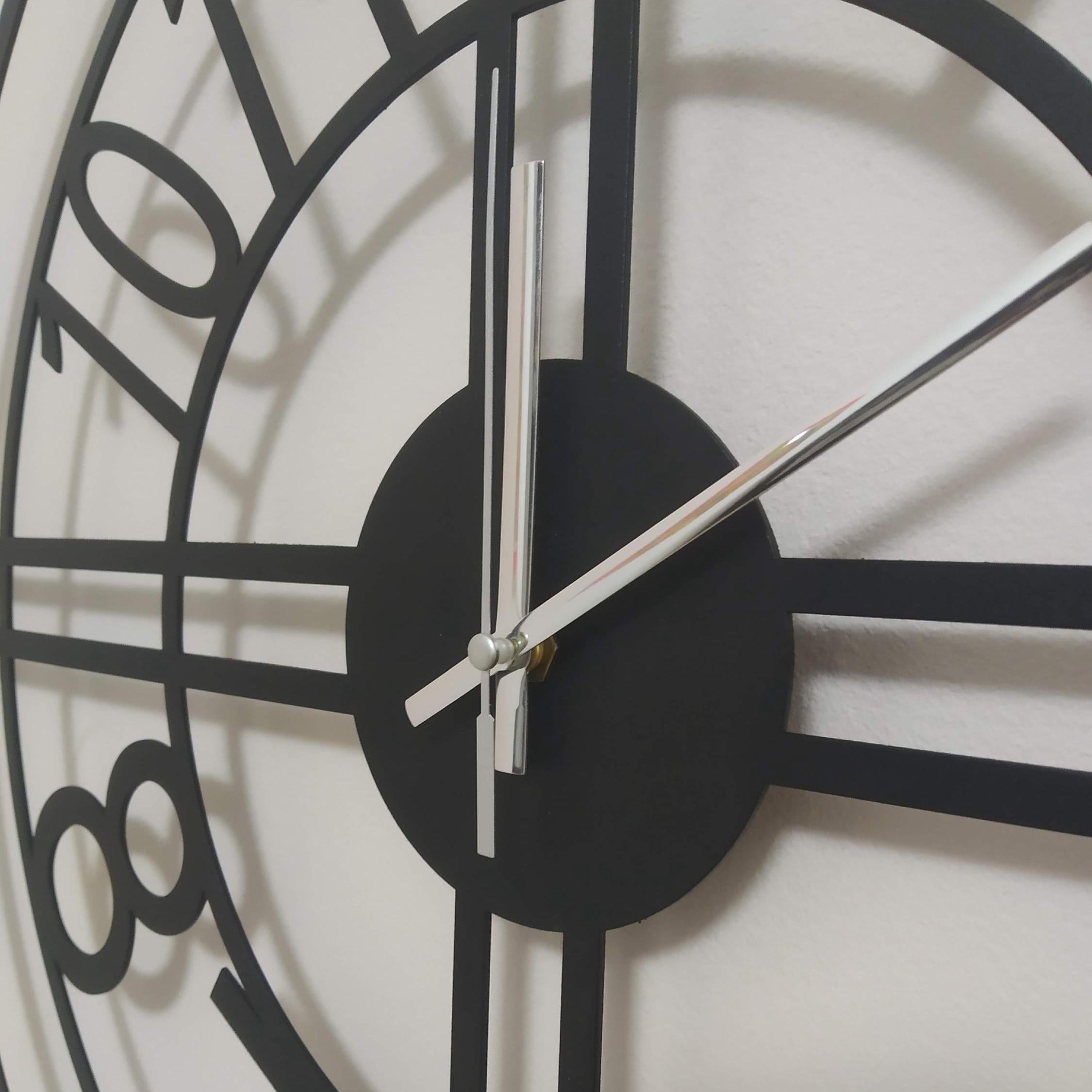 Close-up of a black wall clock with white hands on a light background
