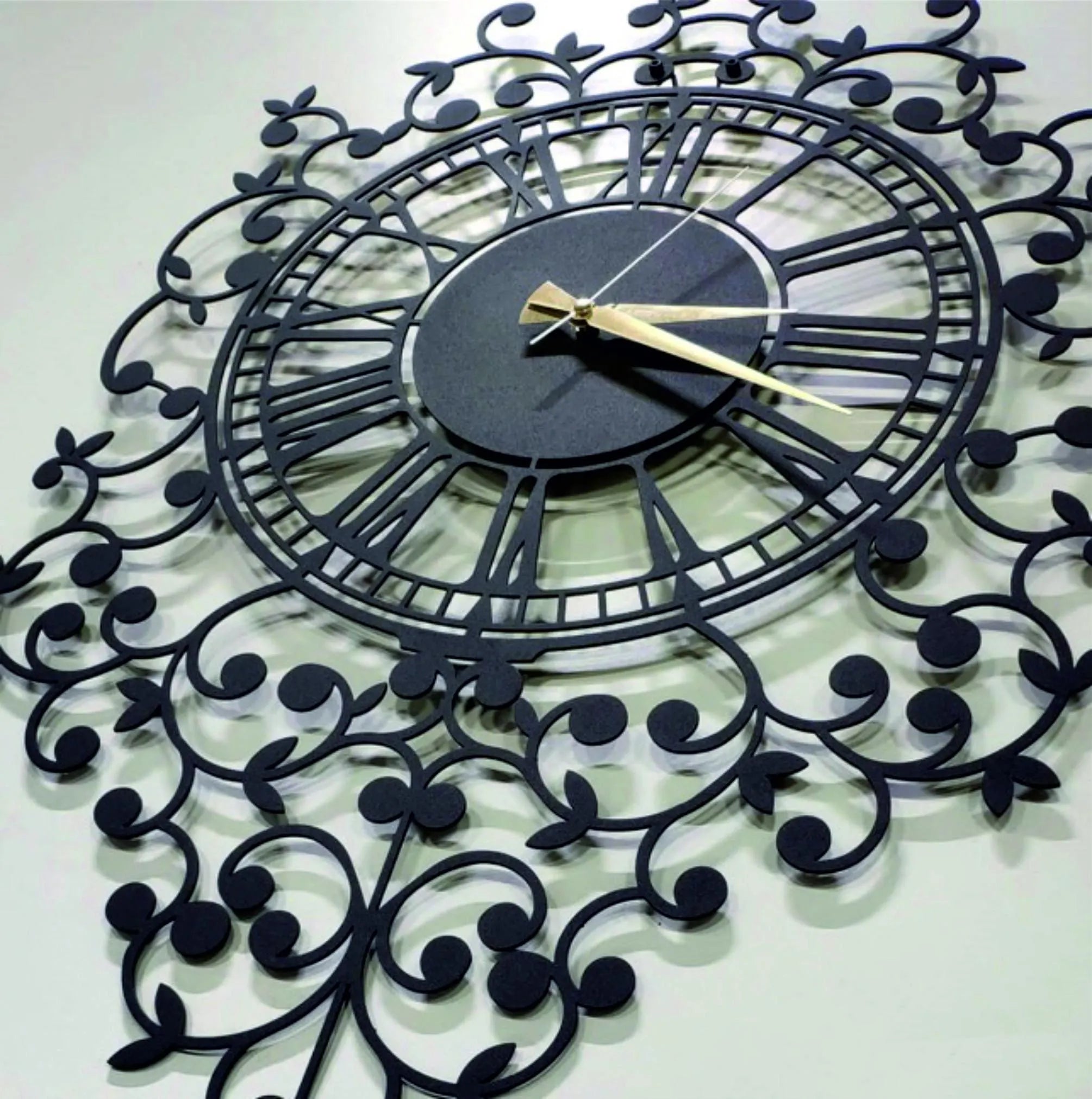 Decorative wall clock with intricate black metal design on a white background