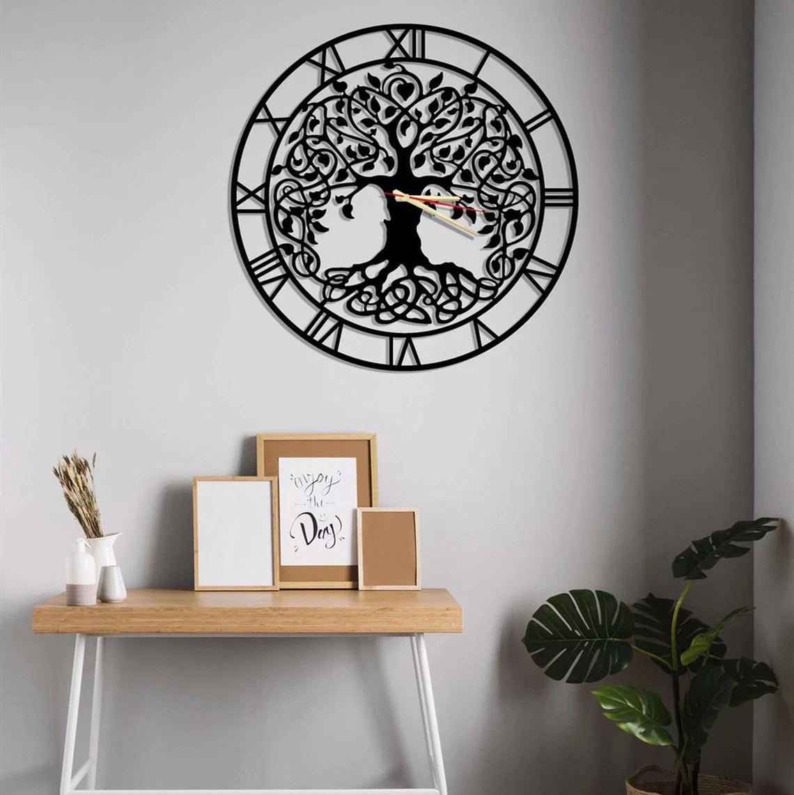 Decorative wall clock with tree design on a gray wall above a wooden console table.
