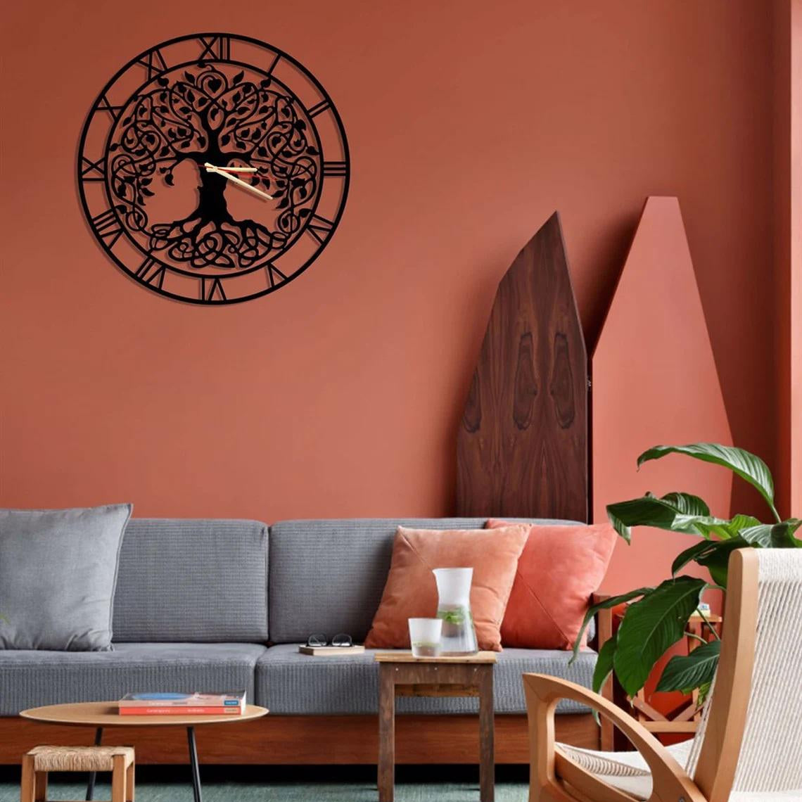 Decorative wall clock with tree design on a warm-toned wall above a gray sofa.
