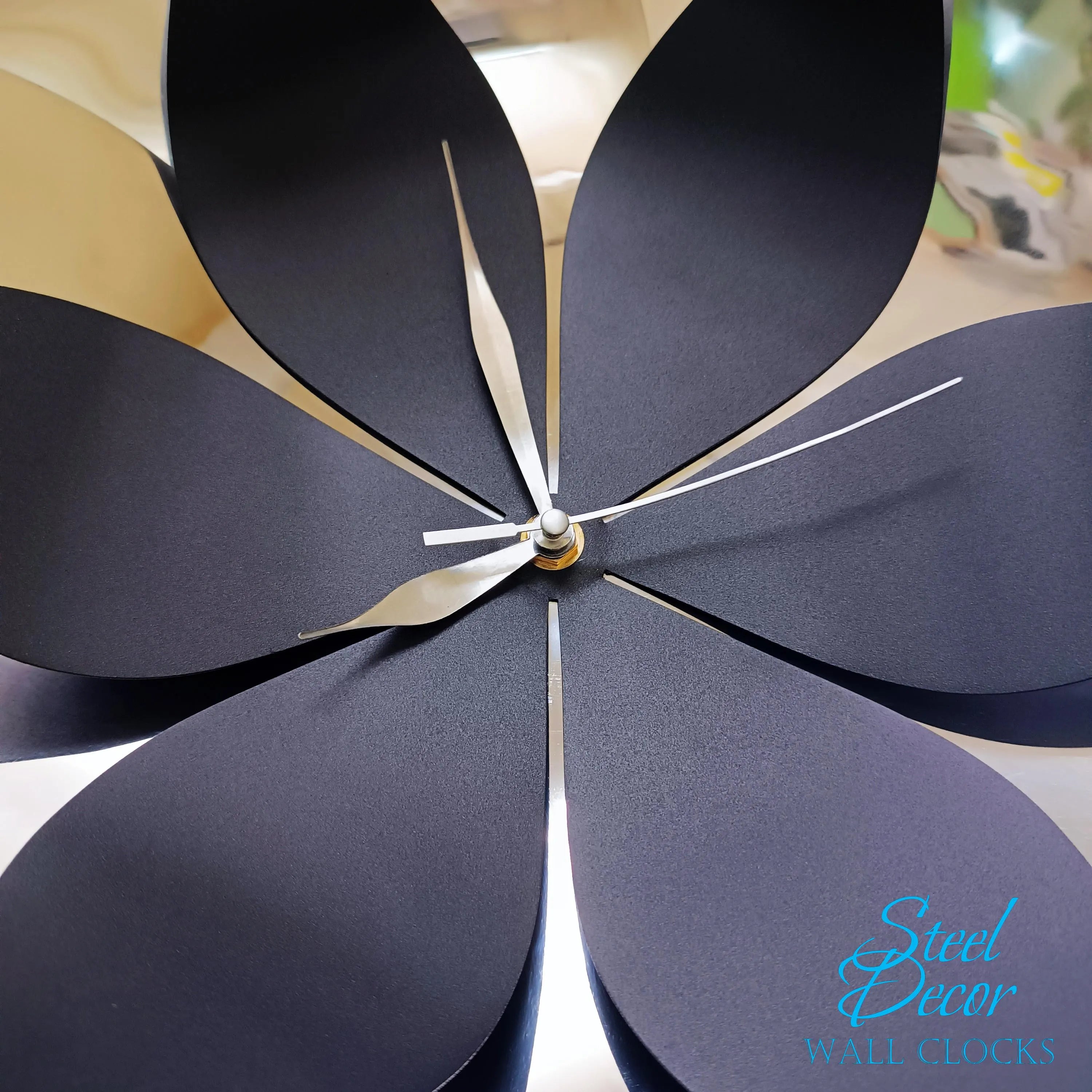 Decorative wall clock with black petal-like design and 'Steel Decor' branding.