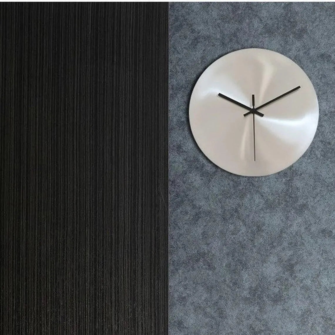 Silver wall clock on a textured gray wall