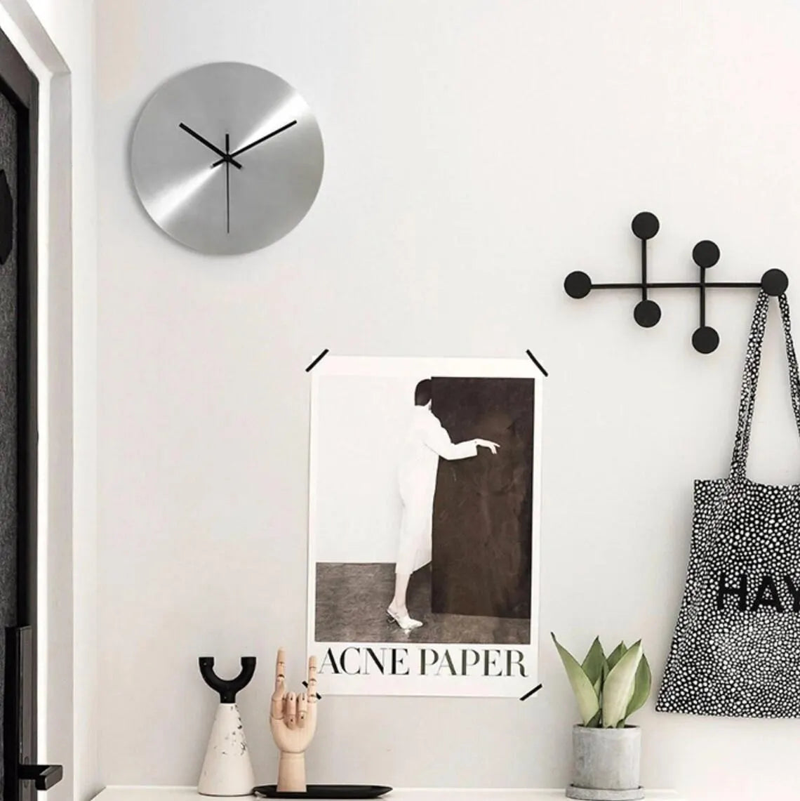 Modern interior with a clock, poster, and decorative items on a white wall.